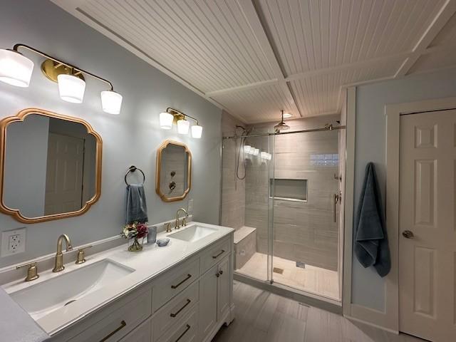 full bath with double vanity, wood finished floors, a sink, and a shower stall