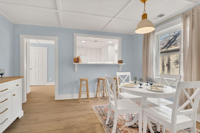 dining room with light wood-type flooring, visible vents, and baseboards