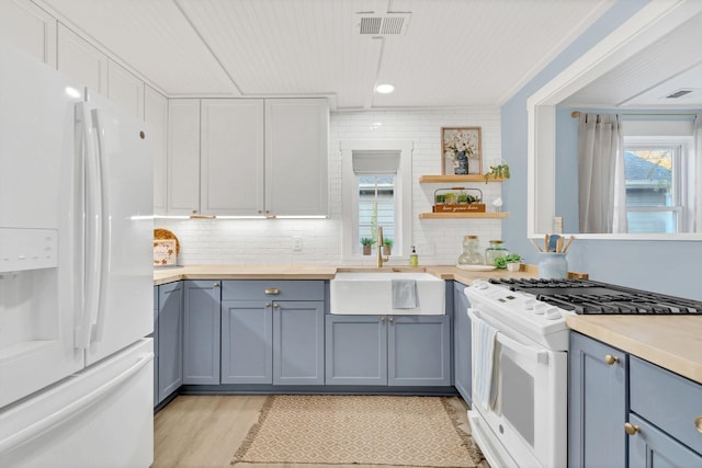 kitchen featuring gray cabinetry, white appliances, a sink, visible vents, and decorative backsplash