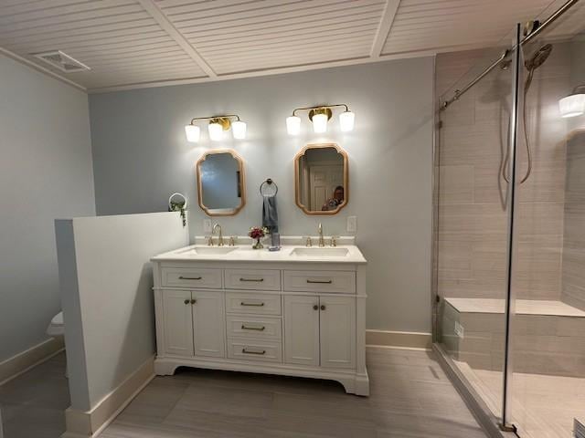 bathroom featuring double vanity, tiled shower, and a sink