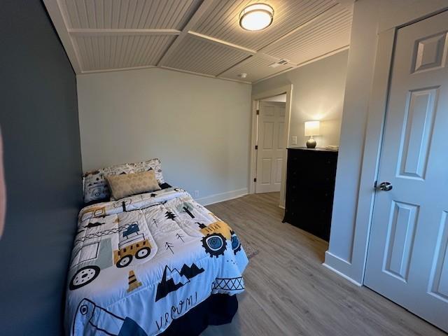 bedroom with vaulted ceiling, baseboards, and wood finished floors