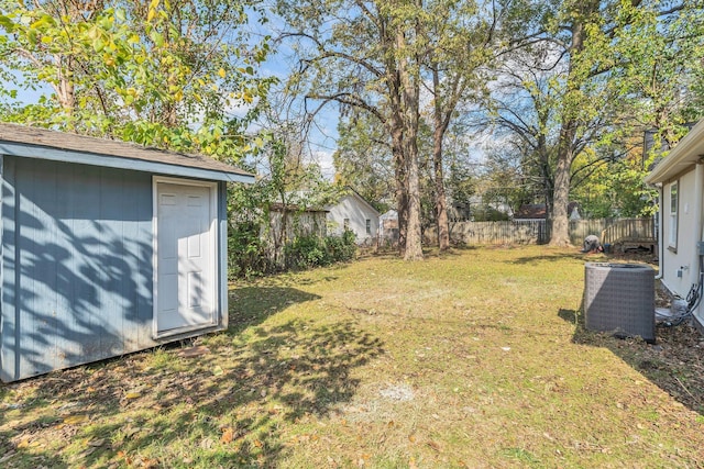 view of yard featuring central air condition unit, a storage unit, fence, and an outbuilding