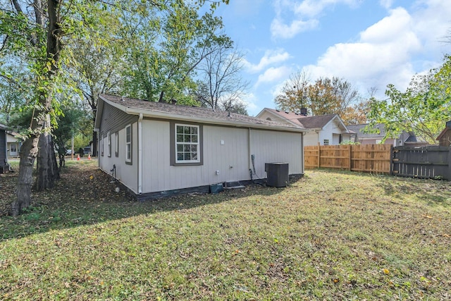 rear view of property featuring a lawn, fence, and central air condition unit