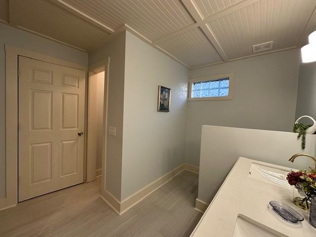 bathroom featuring visible vents, a sink, baseboards, and wood finished floors