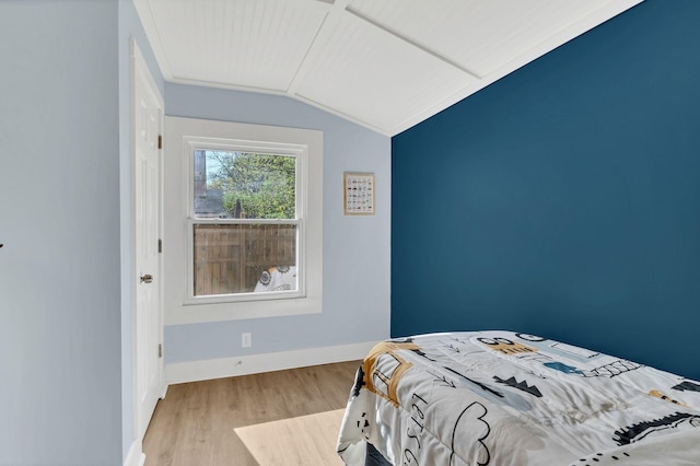 bedroom featuring baseboards, vaulted ceiling, and wood finished floors