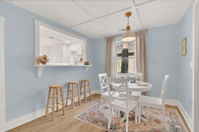 dining space featuring light wood finished floors, visible vents, and baseboards