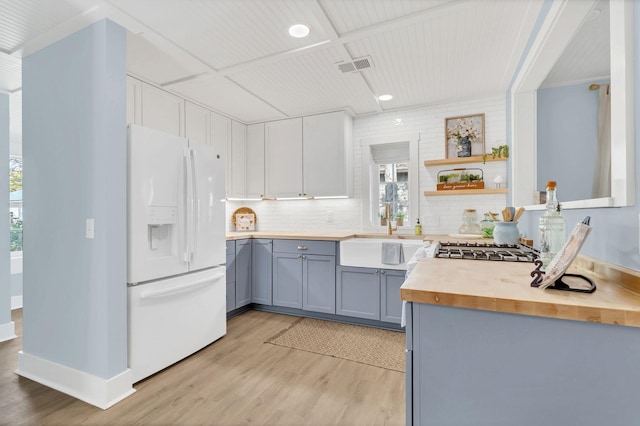 kitchen with light wood-style flooring, gray cabinetry, white refrigerator with ice dispenser, butcher block countertops, and a sink