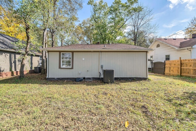 rear view of house with a lawn, fence, and central air condition unit