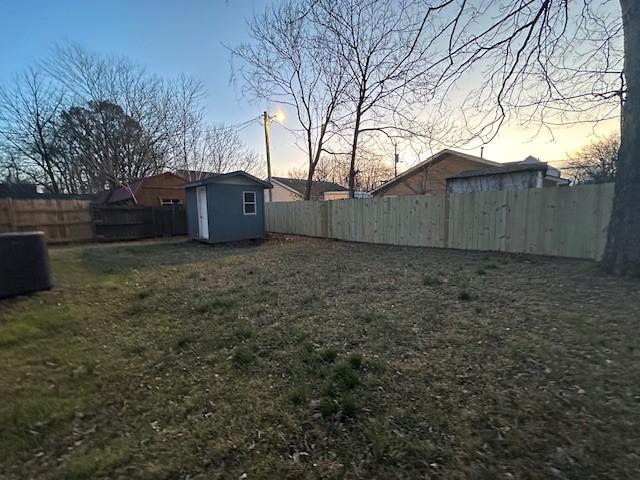 view of yard featuring an outbuilding, a fenced backyard, and a storage unit