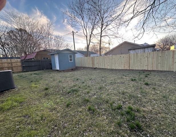 view of yard featuring a storage shed, an outdoor structure, and a fenced backyard