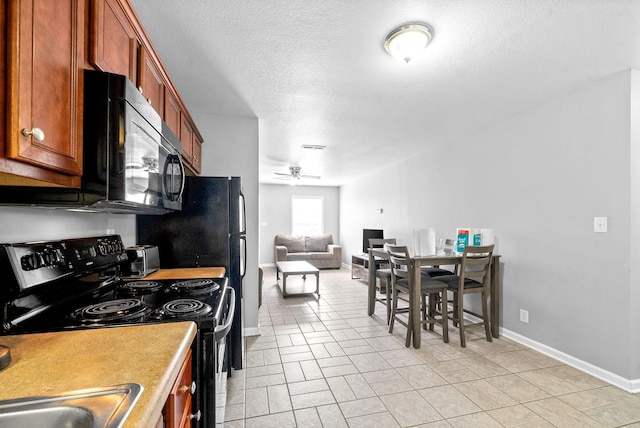 kitchen featuring electric range, ceiling fan, and a textured ceiling