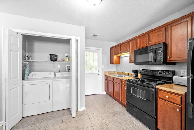 kitchen featuring washing machine and clothes dryer, sink, black appliances, and a textured ceiling