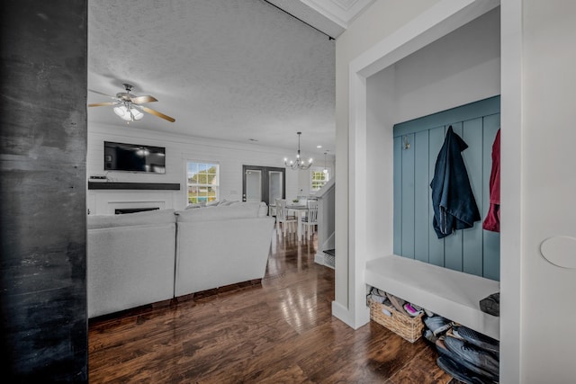 mudroom with a textured ceiling, ceiling fan with notable chandelier, a fireplace, and dark wood-type flooring