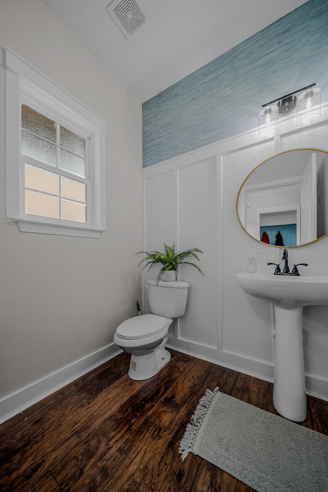 bathroom with wood-type flooring, a textured ceiling, and toilet