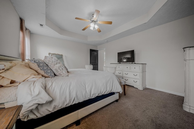 carpeted bedroom featuring ceiling fan and a tray ceiling