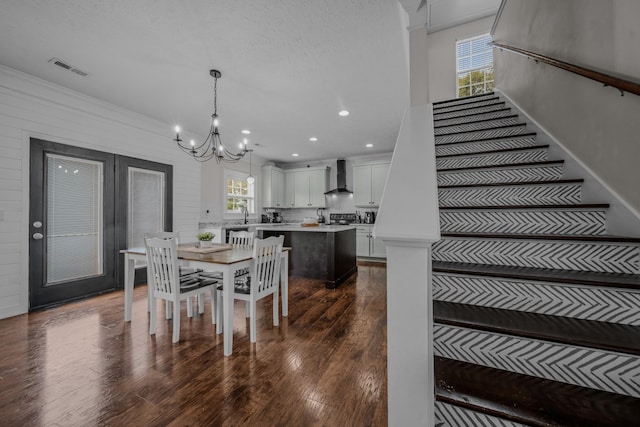 dining space with a textured ceiling, dark hardwood / wood-style floors, an inviting chandelier, and ornamental molding