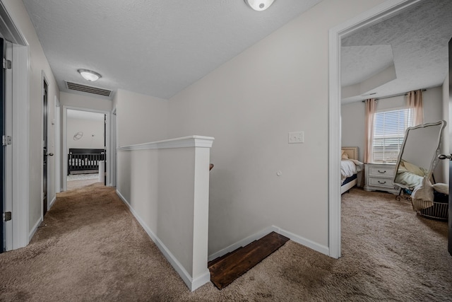 hallway featuring carpet flooring and a textured ceiling