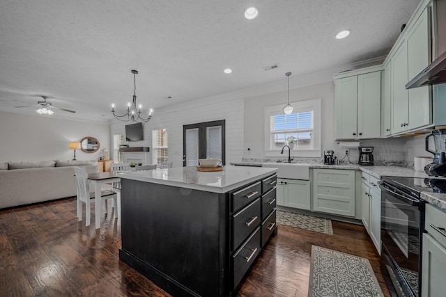 kitchen featuring electric range, a center island, sink, a textured ceiling, and ceiling fan with notable chandelier