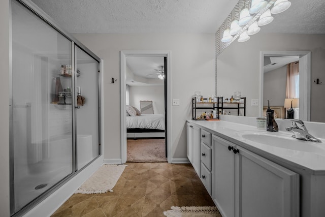 bathroom with ceiling fan, vanity, an enclosed shower, and a textured ceiling