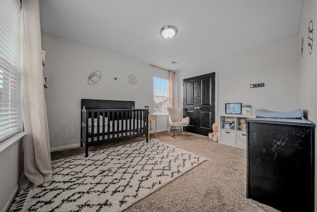 carpeted bedroom featuring a nursery area