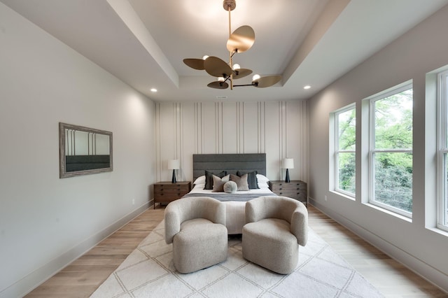 bedroom featuring a raised ceiling, light hardwood / wood-style flooring, and a notable chandelier