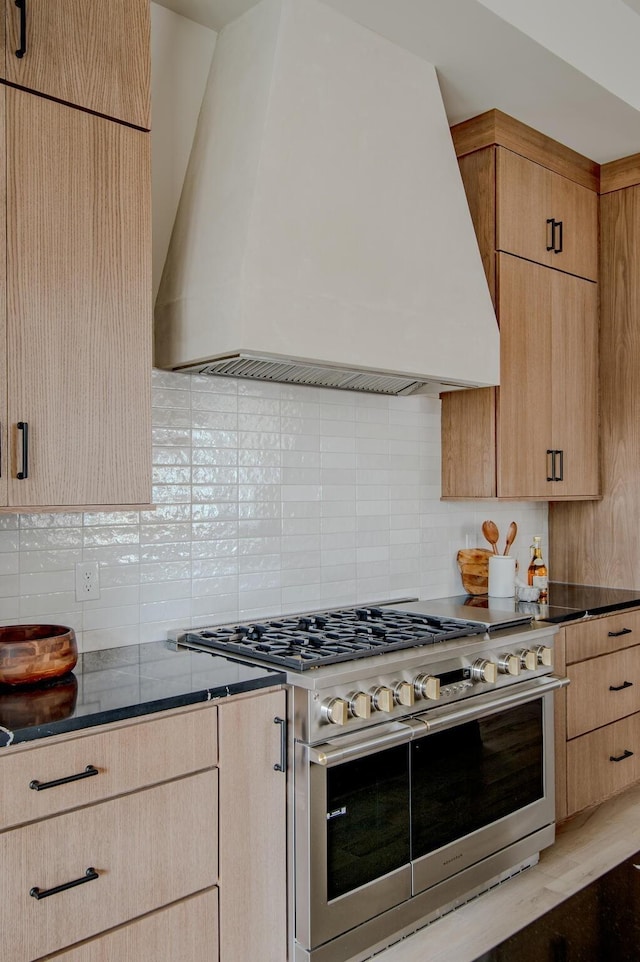 kitchen featuring premium range hood, light brown cabinetry, tasteful backsplash, and double oven range