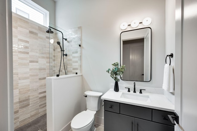 bathroom with vanity, toilet, and tiled shower