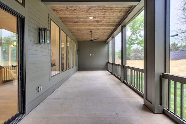 unfurnished sunroom featuring ceiling fan, a healthy amount of sunlight, and wood ceiling