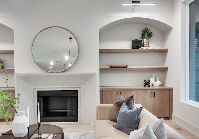 living room featuring built in shelves and light wood-type flooring