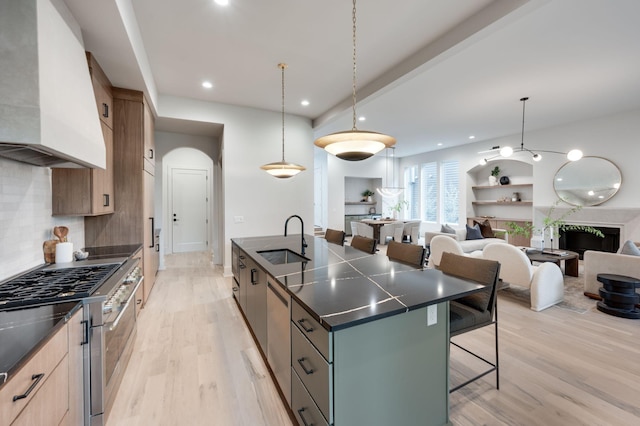 kitchen with pendant lighting, a center island, range hood, and sink