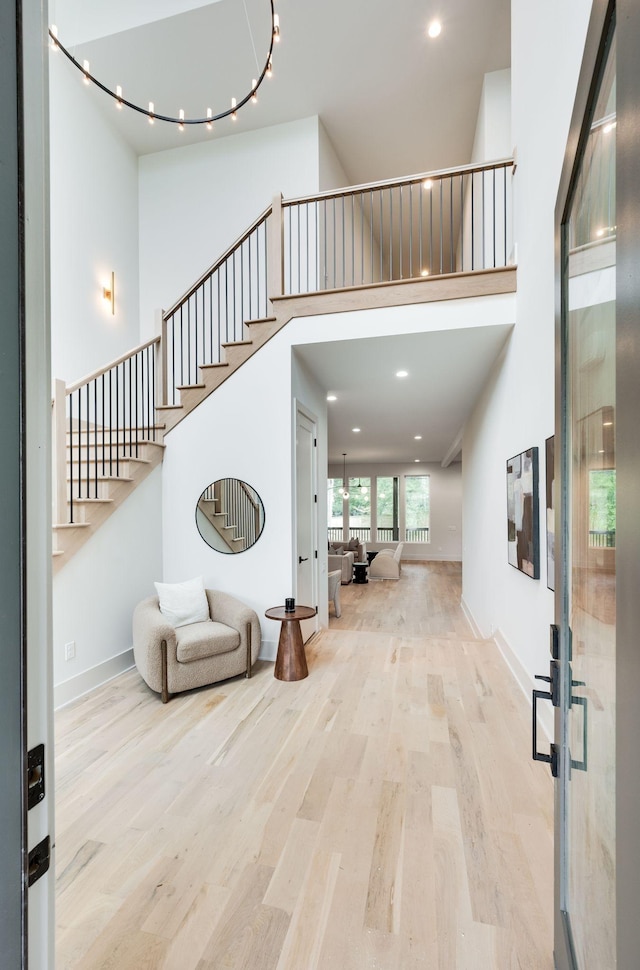 foyer with light wood-type flooring, a towering ceiling, and french doors