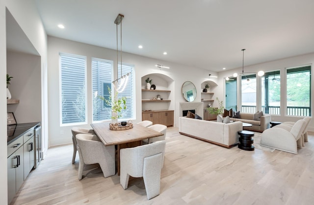 dining space with built in shelves and light hardwood / wood-style flooring