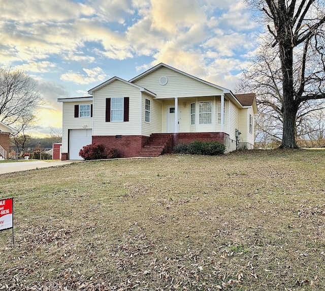 view of front facade with covered porch, a yard, and a garage