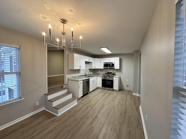 kitchen featuring an inviting chandelier, white cabinets, sink, light hardwood / wood-style flooring, and stainless steel appliances