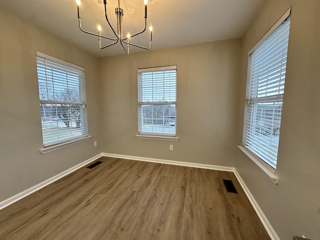 spare room featuring hardwood / wood-style flooring and an inviting chandelier