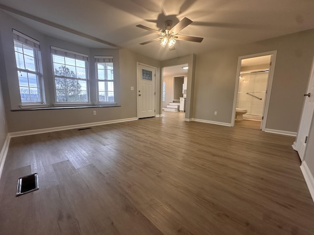 unfurnished bedroom with ceiling fan, ensuite bathroom, and dark wood-type flooring