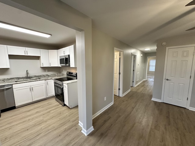 kitchen with sink, white cabinets, light hardwood / wood-style flooring, and appliances with stainless steel finishes