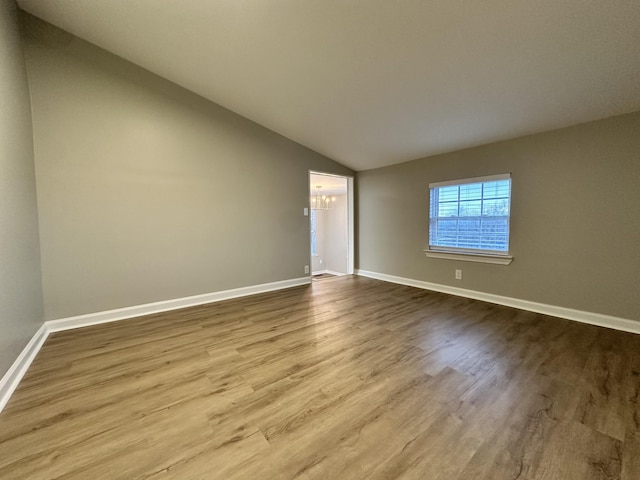 empty room with light hardwood / wood-style floors, lofted ceiling, and an inviting chandelier