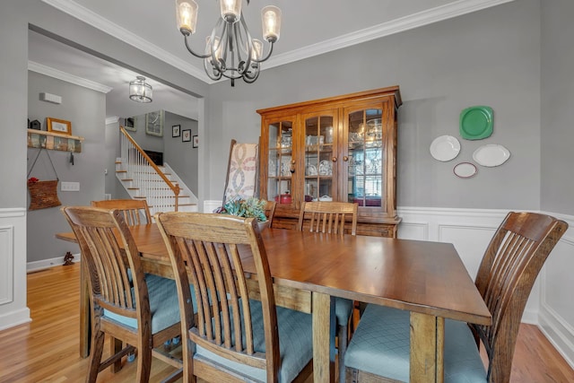 dining space featuring light hardwood / wood-style flooring, crown molding, and a notable chandelier