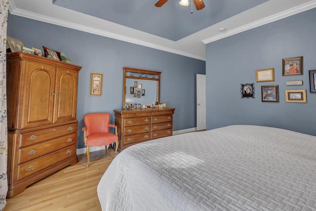 bedroom featuring ceiling fan, a raised ceiling, ornamental molding, and light hardwood / wood-style flooring