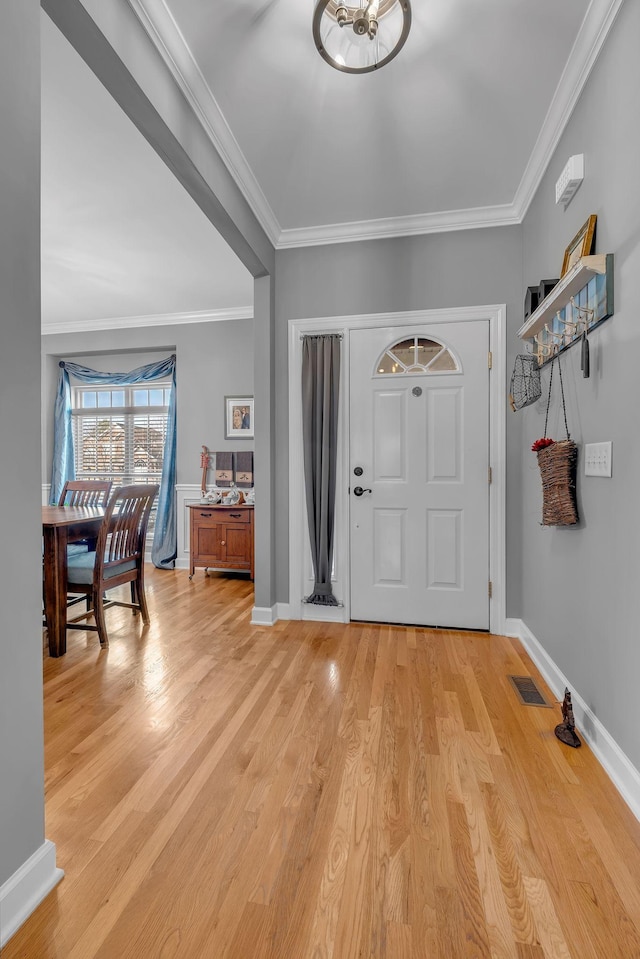 foyer entrance with crown molding and light hardwood / wood-style floors