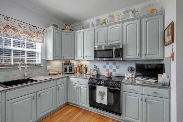 kitchen featuring black electric range, stone countertops, light hardwood / wood-style floors, and sink