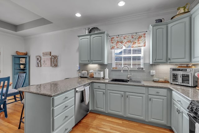 kitchen with sink, stainless steel appliances, tasteful backsplash, light hardwood / wood-style flooring, and kitchen peninsula