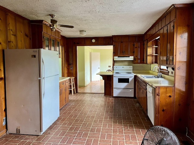 kitchen featuring ceiling fan, white appliances, sink, and wooden walls