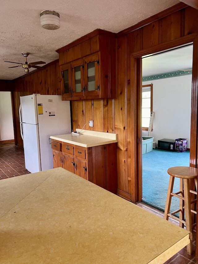 kitchen with a textured ceiling, white fridge, and ceiling fan