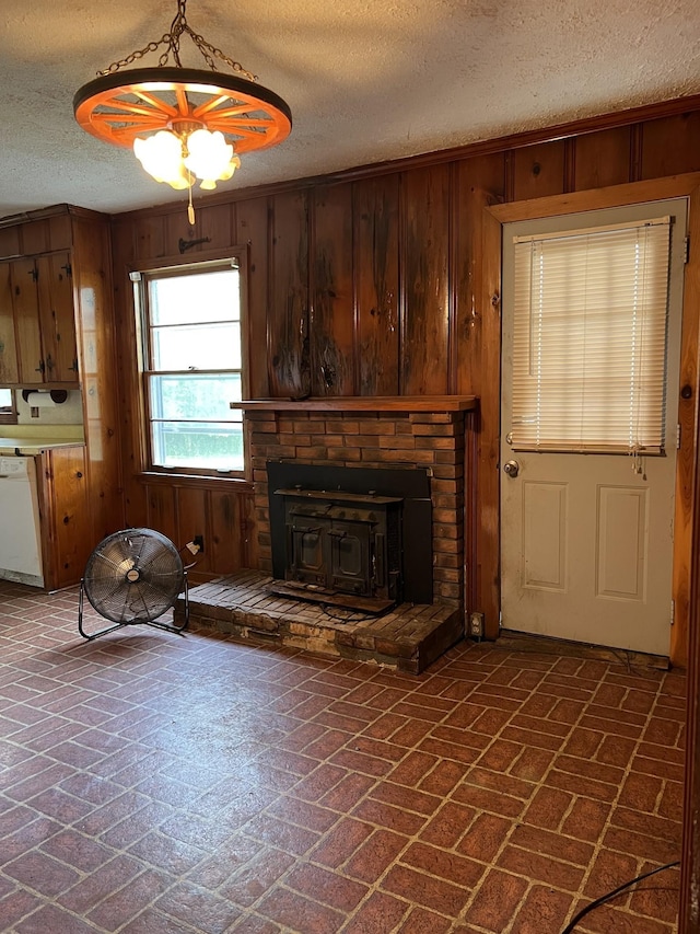 unfurnished living room featuring a textured ceiling, a wood stove, and wood walls