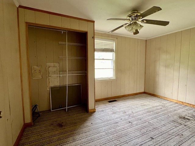 unfurnished bedroom featuring ceiling fan, crown molding, and wood walls