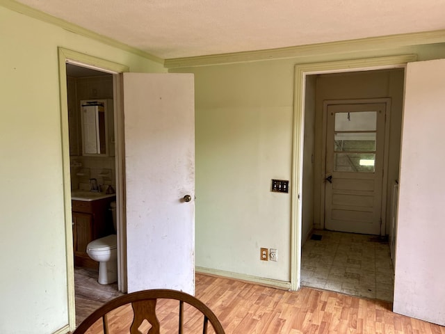 hallway featuring light hardwood / wood-style floors, crown molding, and sink