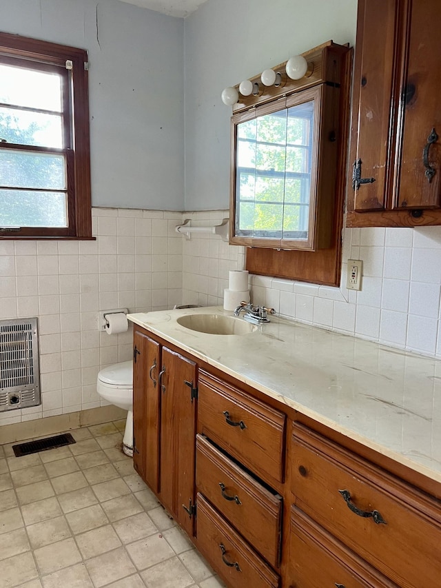 bathroom featuring vanity, toilet, plenty of natural light, and heating unit