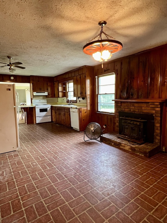 kitchen featuring white appliances, ceiling fan, sink, decorative light fixtures, and wood walls